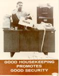 cx-6968-003jpg-An office setting with a guy sitting on top of a very cluttered desk with a holding a sign that says, "violation."  Underneath the poster it stated, "Good Housekeeping Promotes Good Security."

